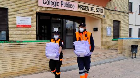 Joana Cajidor (izda.) y Osama Ihdi salen del colegio de Caparroso con las tareas para los alumnos.