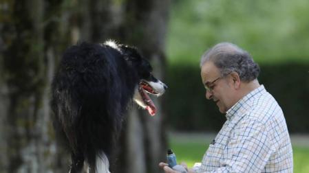 Un hombre con su perro subido a un monolito del paseo del Arga.