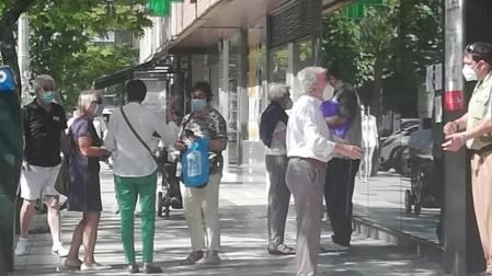 El vigilante de seguridad informa a un contribuyente de las reglas para ser atendido mientras otro grupo de afectados comparte su malestar.