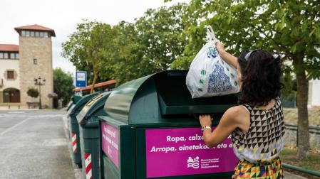Una persona deposita una bolsa con ropa en un contenedor de Esquíroz.