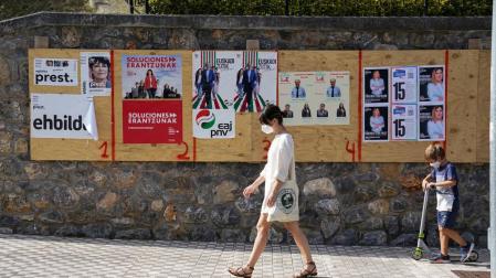 Una mujer camina en Ordizia delante de unos carteles electorales.