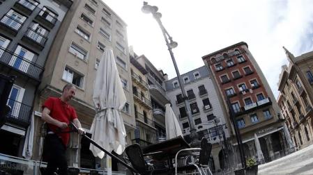 El dueño de un bar de la Plaza del Castillo desinfecta su terraza.