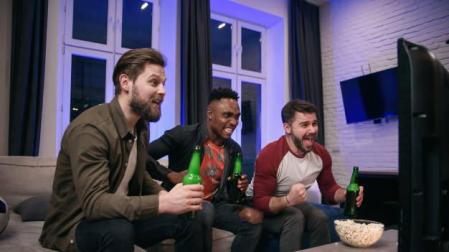 Tres amigos siguen un partido de la NBA por televisión