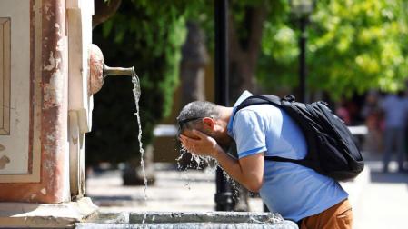 Un hombre se refresca en una de las fuentes del interior del Patio de los Naranjos de la Catedral de Córdoba
