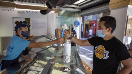Varias personas comen helados, en cucurucho, en tarrina o en corte por las calles de Pamplona pese a la incomodidad de las mascarillas.