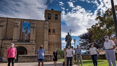 Algunos de los socios de la cofradía Amigos de San Veremundo en la entrada de la parroquia,  junto con la estatua del patrón de la localidad.
