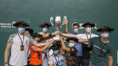 Los ocho pelotaris de Pamplona y su entrenador, Iñaki Barbajero, alzan el trofeo de campeones.