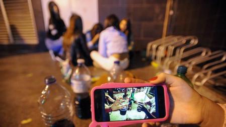 Un grupo de adolescentes hace botellón en la calle.