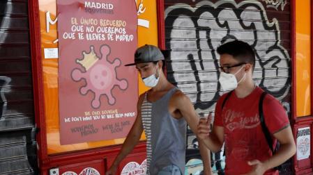 Dos jóvenes pasean con mascarilla por una calle de Madrid