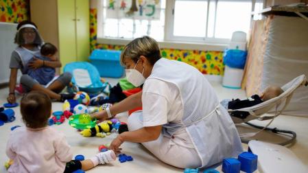Niños en una guardería con sus cuidadoras cumpliendo las medidas de seguridad