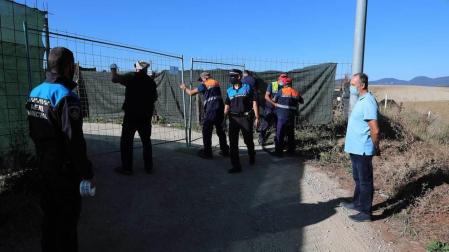 A la derecha, Tomás Labiano, propietario del terreno, observa cómo agentes y empleados municipales proceden al precinto de la instalación en Paternáin.