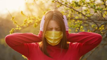 Una mujer con mascarilla se tapa los oídos.