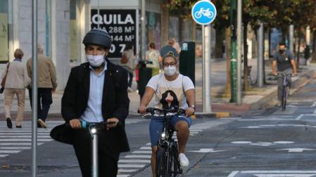 Un ciclista y un patín eléctrico recorren la avenida de Bayona.