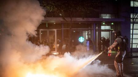 Un agente apaga las llamas de un cóctel molotov.