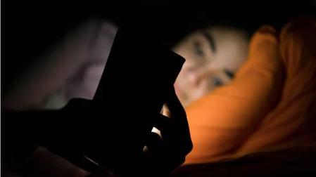 Una persona, con un móvil en la cama.