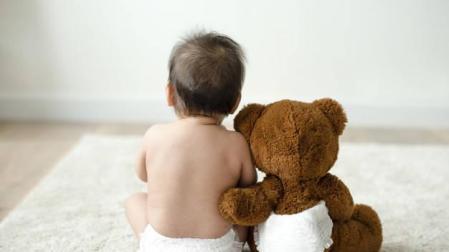 Imagen de un bebé con un osito de peluche