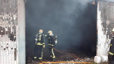Dos bomberos, en la puerta de la nave que ha ardido.