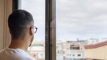 Imagen de un hombre mirando por la ventana