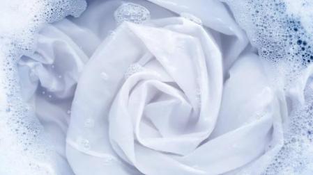 Imagen de ropa blanca sumergida en agua con detergente