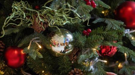 Una mujer, reflejada en la bola de un árbol navideño.