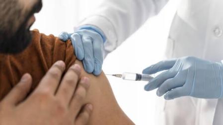 Imagen de un sanitario inyectando una vacuna a un paciente
