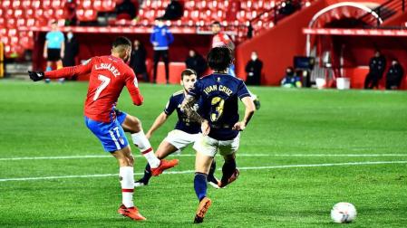 El delantero colombiano del Granada Luis Suárez golpea el balón ante dos rivales de Osasuna,