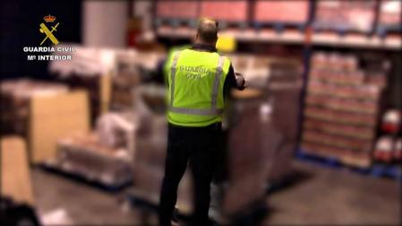 Un guardia civil examina una de las cajas de botellas de ron falsificadas