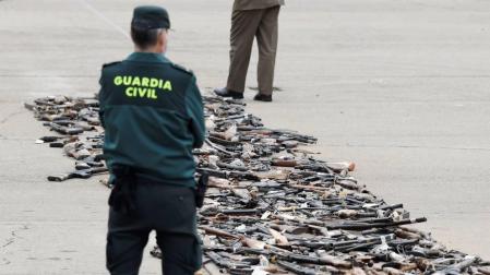 Un Guardia Civil observa los de varios centenares de armas incautadas en décadas pasadas a las bandas terroristas ETA y GRAPO antes de ser destruidas durante el acto celebrado en la Academia de la Guardia Civil de Valdemoro (Madrid).