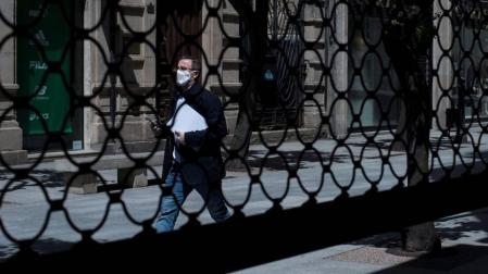 Un hombre camina por una calle por delante de la persiana semibajada de un comercio en los meses más duros de la pandemia.