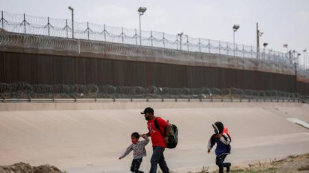 Un padre con dos niños intentan cruzar la frontera entre México y Estados Unidos atravesando el río Bravo