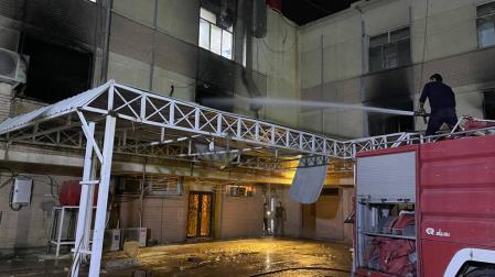 Un bombero apaga el fuego tras el atentado en el hospital en Bagdad.