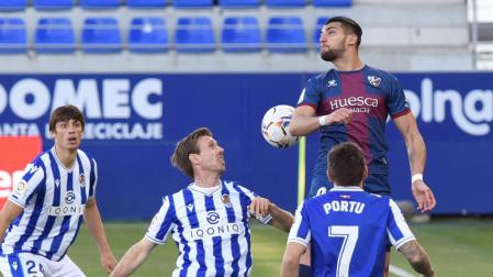 El delantero del Huesca Rafael Mir intenta rematar de cabeza junto a Nacho Monreal de la Real Sociedad