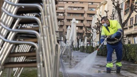 Un operario de limpieza limpia la zona de terrazas de bares del paseo de Invierno de Tudela.
