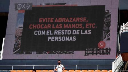 Dos aficionados en Mestalla con un mensaje a sus espaldas.
