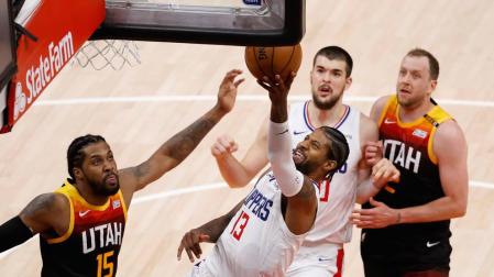 El escolta de Los Angeles Clippers Paul George conduce el balón al aro contra Derrick Favors de Utah Jazz.