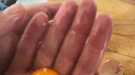 Imagen de una mano separando una yema de huevo de la clara
