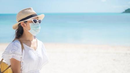 Una mujer con mascarilla en la playa