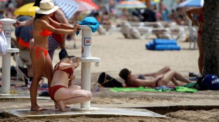 Dos mujeres tratan de refrescarse en los lavapaies de la playa de El Postiguet de Alicante