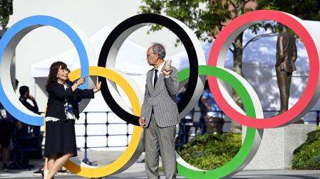 Dos personas posan junto a los anillos olímpicos a la entrada del Estadio Olímpico de Tokio