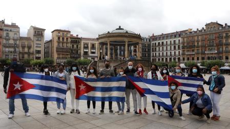 Un grupo de ciudadanos cubanos despliega las banderas del país en la Plaza del Castillo de Pamplona
