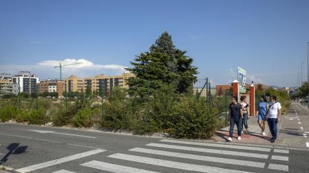 Un grupo de personas pasa por la acera de la avenida Gupúzcoa junto al solar que cobijará un cubo comercial y viviendas