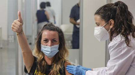 Una joven sonríe y saluda mientras recibe la vacuna contra la Covid-19 de la Ciutat de les Arts i les Ciències de Valencia