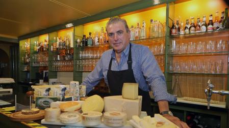 Aitor Otazu Larrauri posa en la barra del bar Savoy con varias tablas de queso