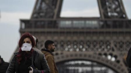 Una mujer pasea en París protegida con una mascarilla