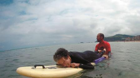 Marian Cano, tumbada sobre una tabla de surf, con un monitor de ‘MOOR Surf Eskola’, en Zarautz (Guipúzcoa), el pasado 3 de julio