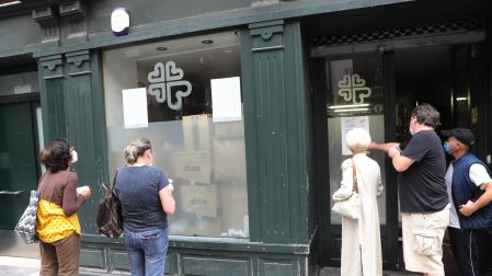 Varias personas comprueban los números, este lunes, en la sede de Cáritas en la calle San Antón