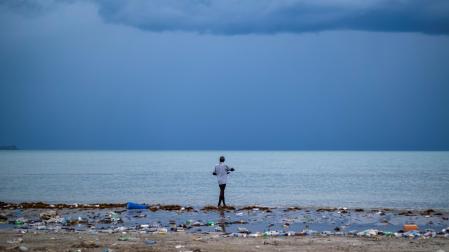 Un hombre pasea por una playa contaminada mientras la tormenta tropical "Grace" se aproxima