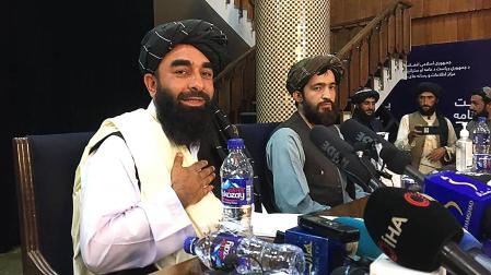 El portavoz talibán Zabihullah Mujahid (izda.)gesticula durante una rueda de prensa en Kabul