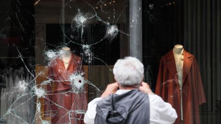 Un hombre observa un escaparate atacado durante la noche en el centro de San Sebastián