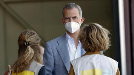 El rey Felipe VI conversa con dos personas durante su visita este sábado al centro de acogida temporal instalado en la base de Torrejón de Ardoz